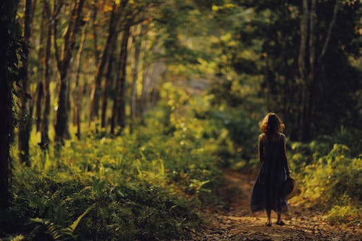 Back view of a woman walking on a forest pathway surrounded by lush trees.