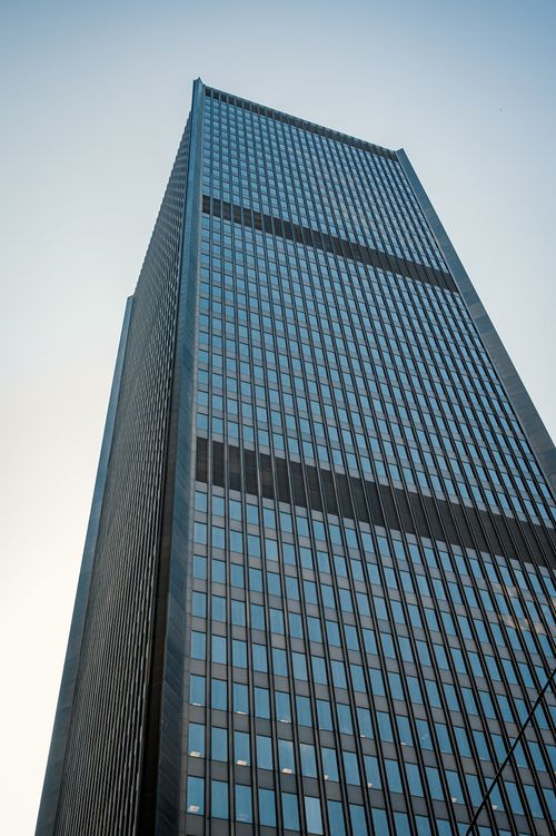 Free Low angle view of a modern skyscraper with glass facade against a blue sky. Stock Photo
