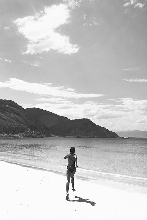 A Woman in Swimsuit Running on Shore