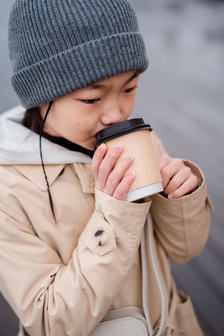 A Girl Drinking Coffee From A Paper Cup