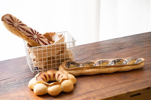 Free Decorative artisanal breads on a rustic wooden table, perfect for bakery enthusiasts. Stock Photo