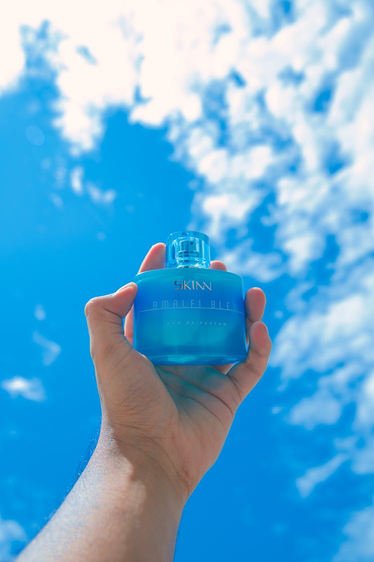 A Person Holding Blue Perfume Bottle 