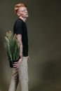 Man in Black Crew Neck Shirt and White Pants Holding Green Plant