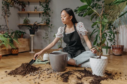 Woman in Black and White Floral Shirt and Gray Pants Sitting on Brown Wooden Table