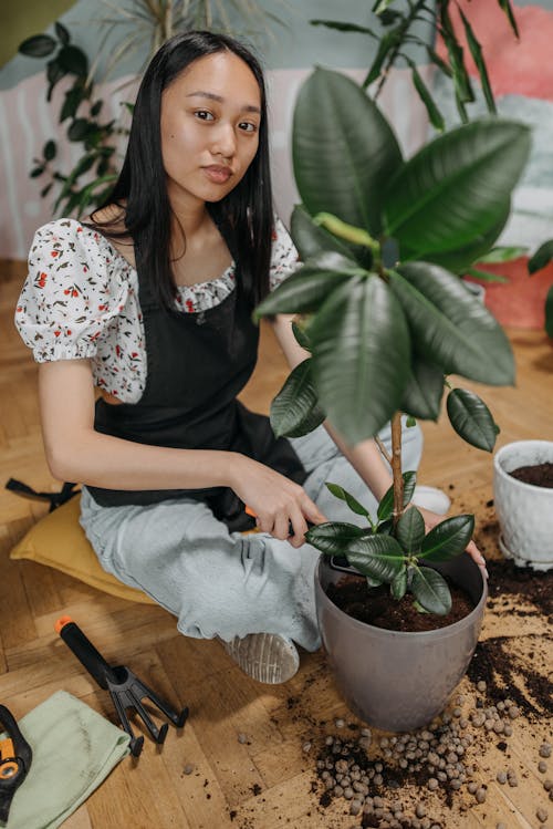 Woman in Black and White Floral Shirt and Gray Pants Sitting on Brown Wooden Chair