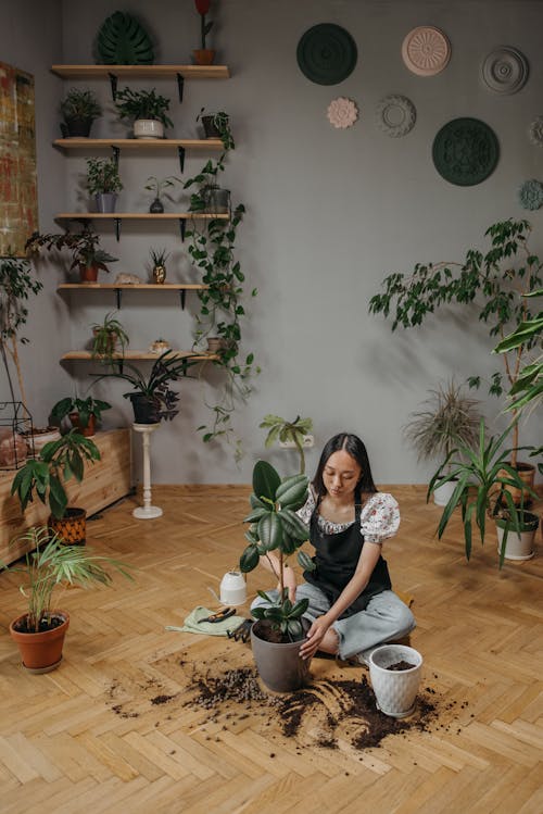 Woman in White and Black Floral Long Sleeve Shirt Sitting on Brown Wooden Floor