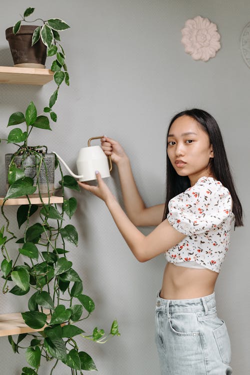 A Woman Watering Her Plant with a Watering Pot