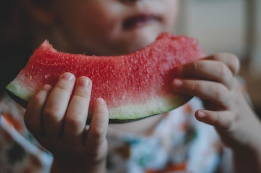 Close-up of a child holding and eating a slice of watermelon. Perfect for summer themes.