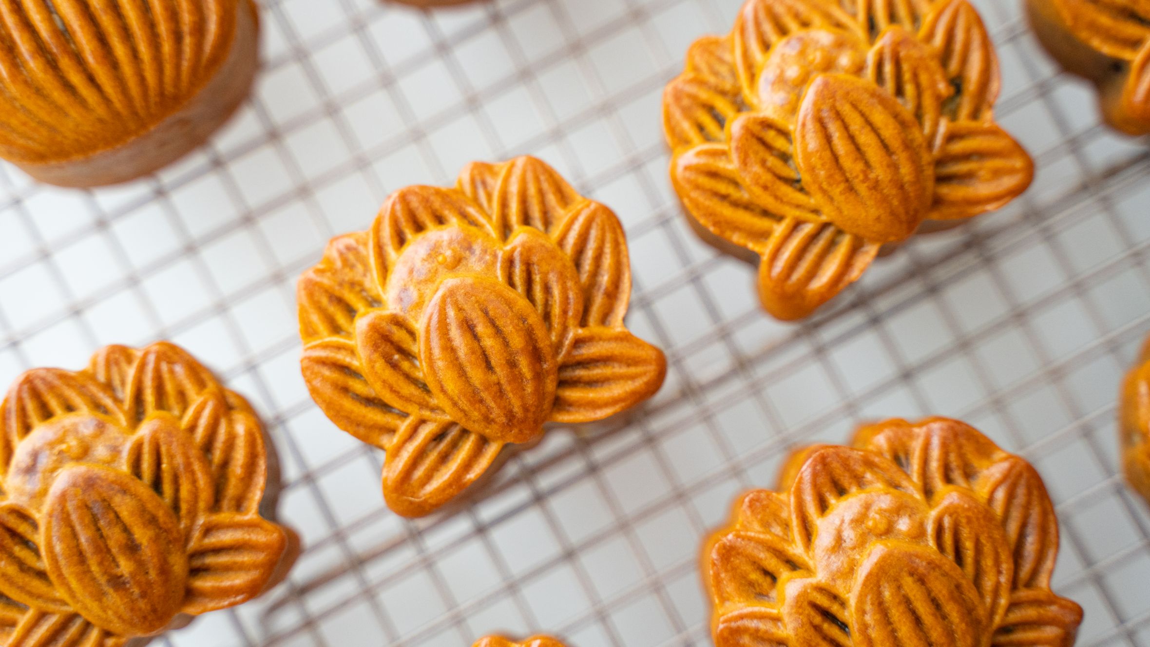 Delicate mooncakes on a cooling rack, showcasing intricate designs. Perfect for Mid-Autumn Festival.
