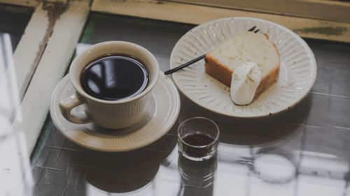 Free A stylish breakfast scene with black coffee and cake on a ceramic plate, perfect for food enthusiasts. Stock Photo