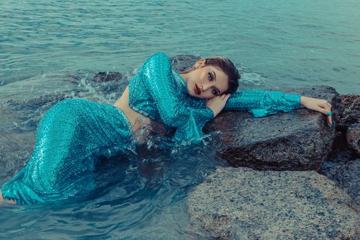 Woman in Teal Dress Lying on Beach Shore