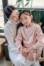 Woman in Pink Long Sleeve Shirt Hugging Girl in White Long Sleeve Shirt