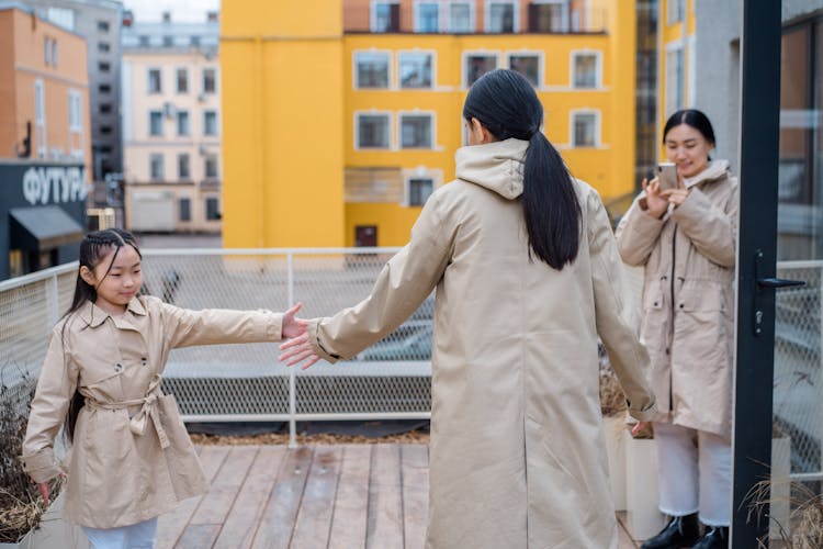 Woman Photographing Mother And Child Holding Hands