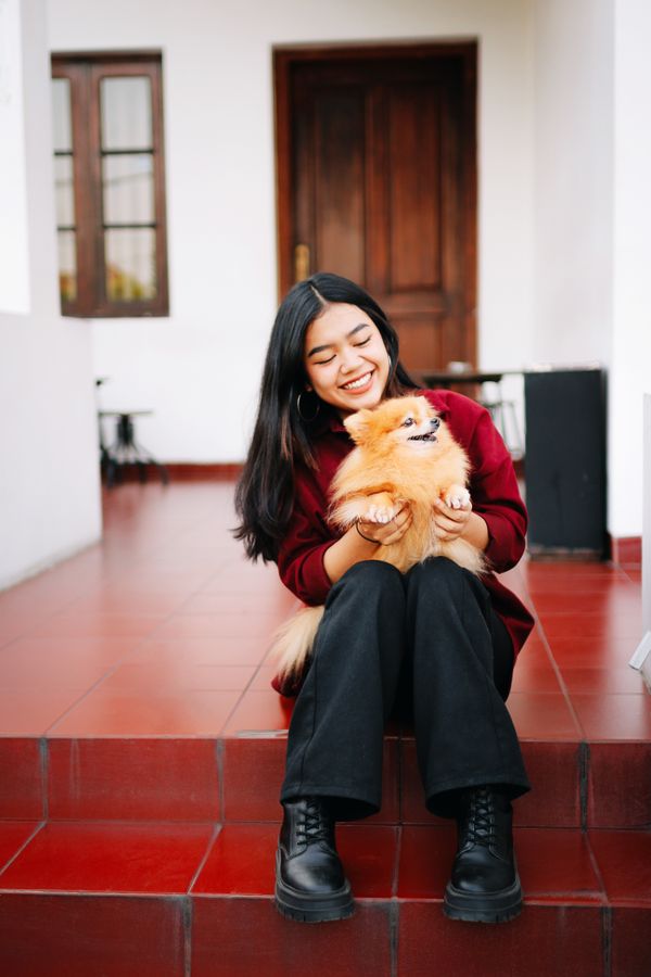 Sophie Lane sitting on the steps holding a Pomeranian dog