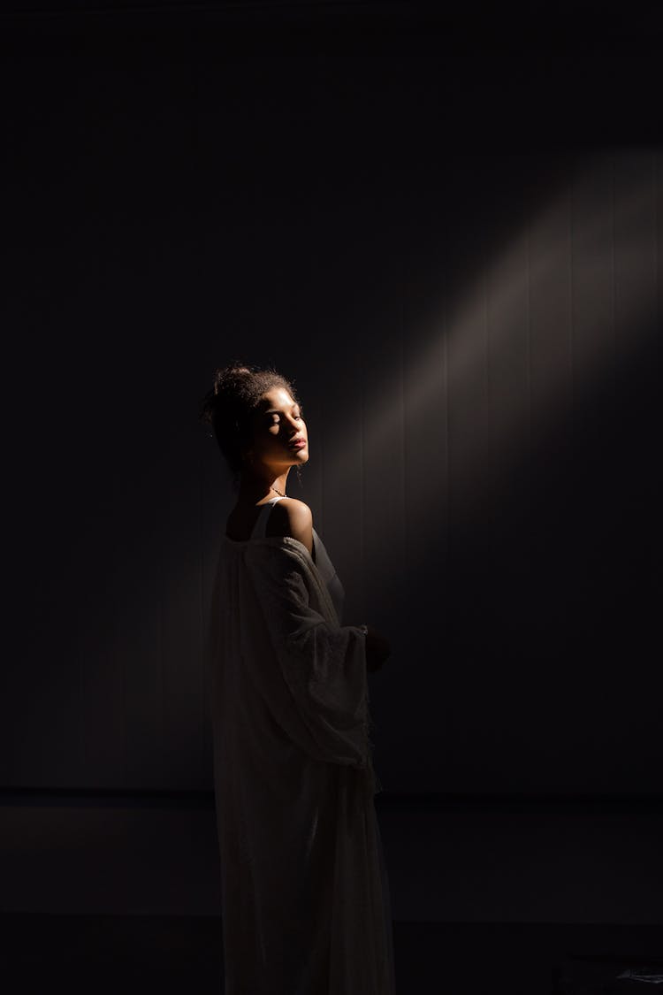 Sun Rays Falling On A Young Woman In A Dark Room 