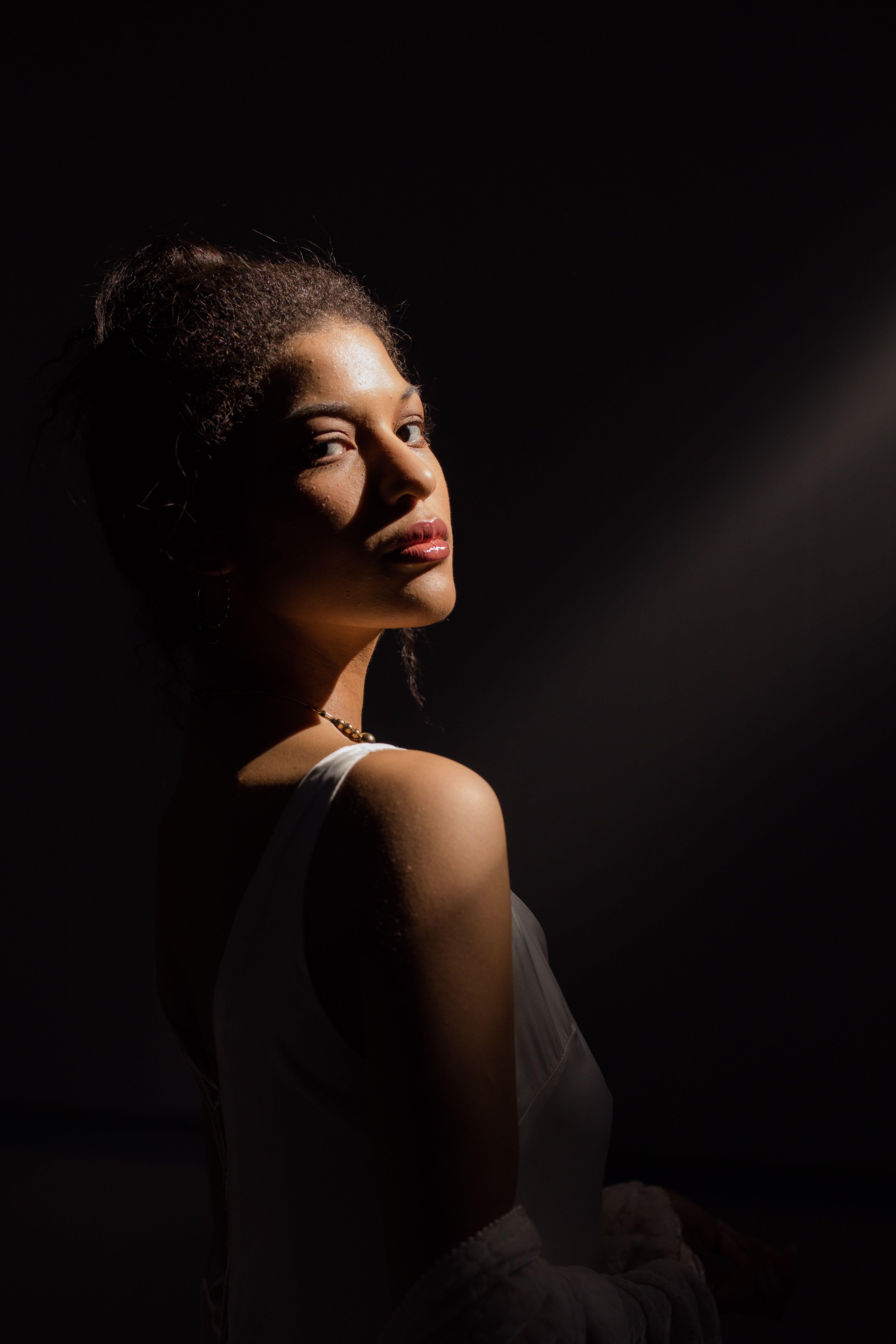 Captivating portrait of a woman in a white top with striking dramatic lighting.