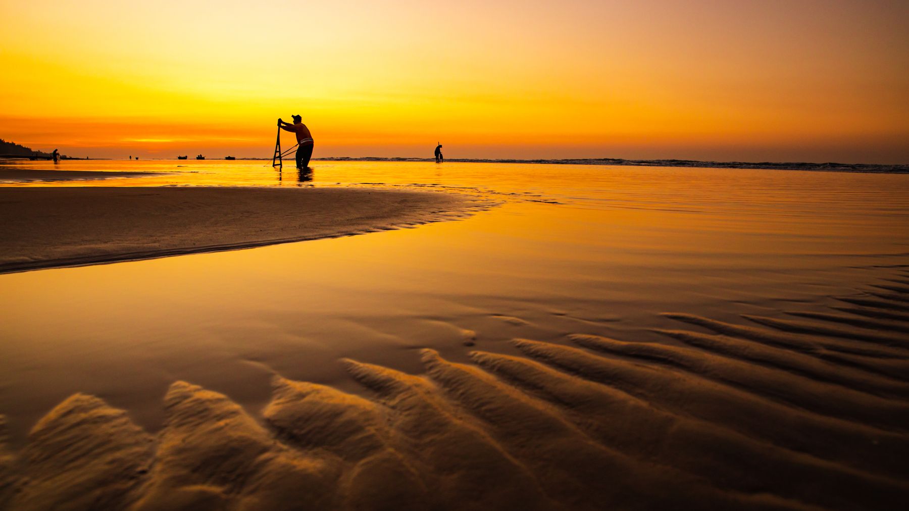 Silhouettes of people at Hồ Tràm Beach during a stunning golden sunset.