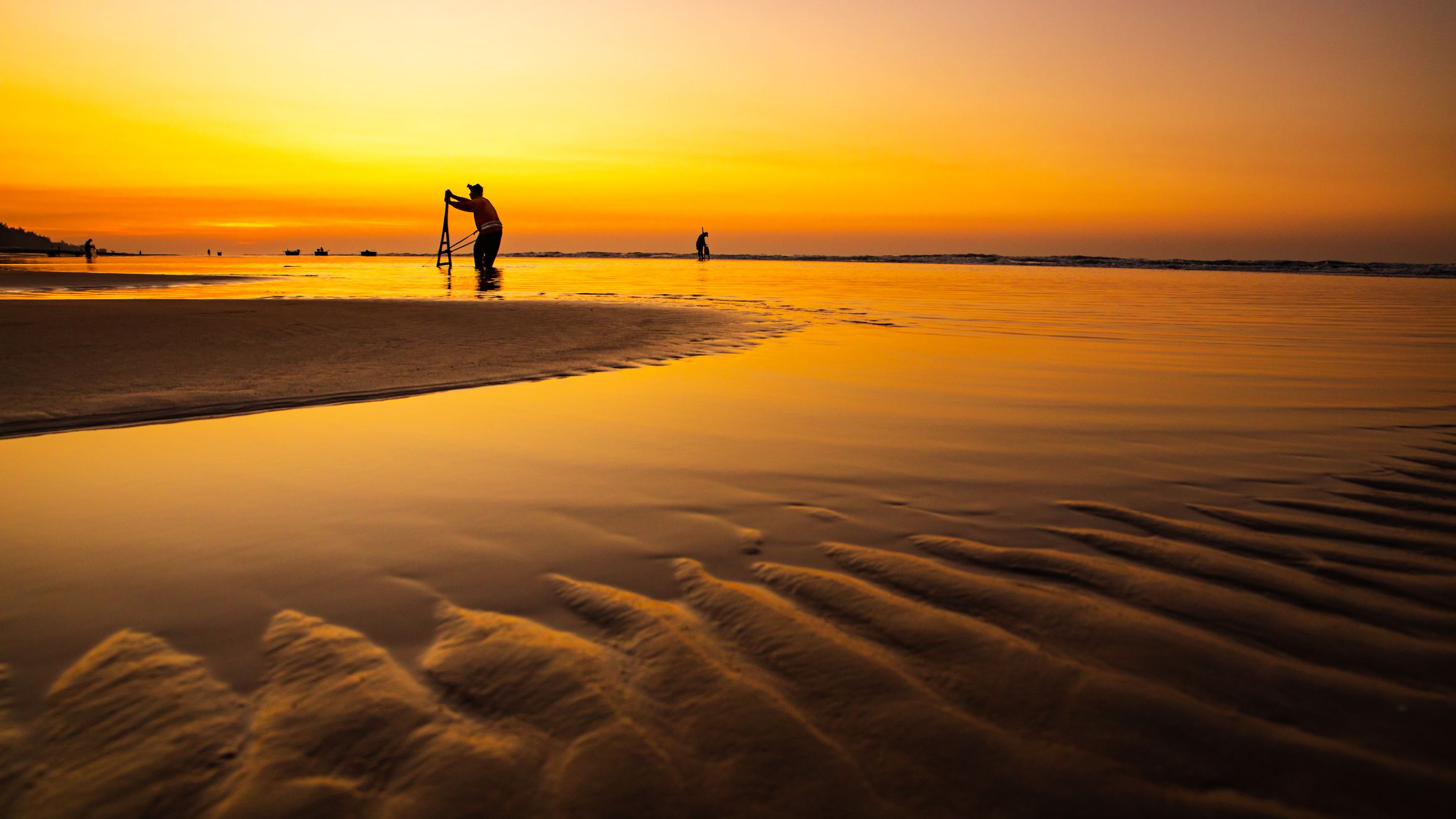 Silhouettes of people at Hồ Tràm Beach during a stunning golden sunset.