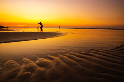 Silhouettes of people at Hồ Tràm Beach during a stunning golden sunset.