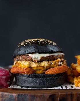 Close-up of a gourmet burger with a black bun and fries. Perfect for food photography.