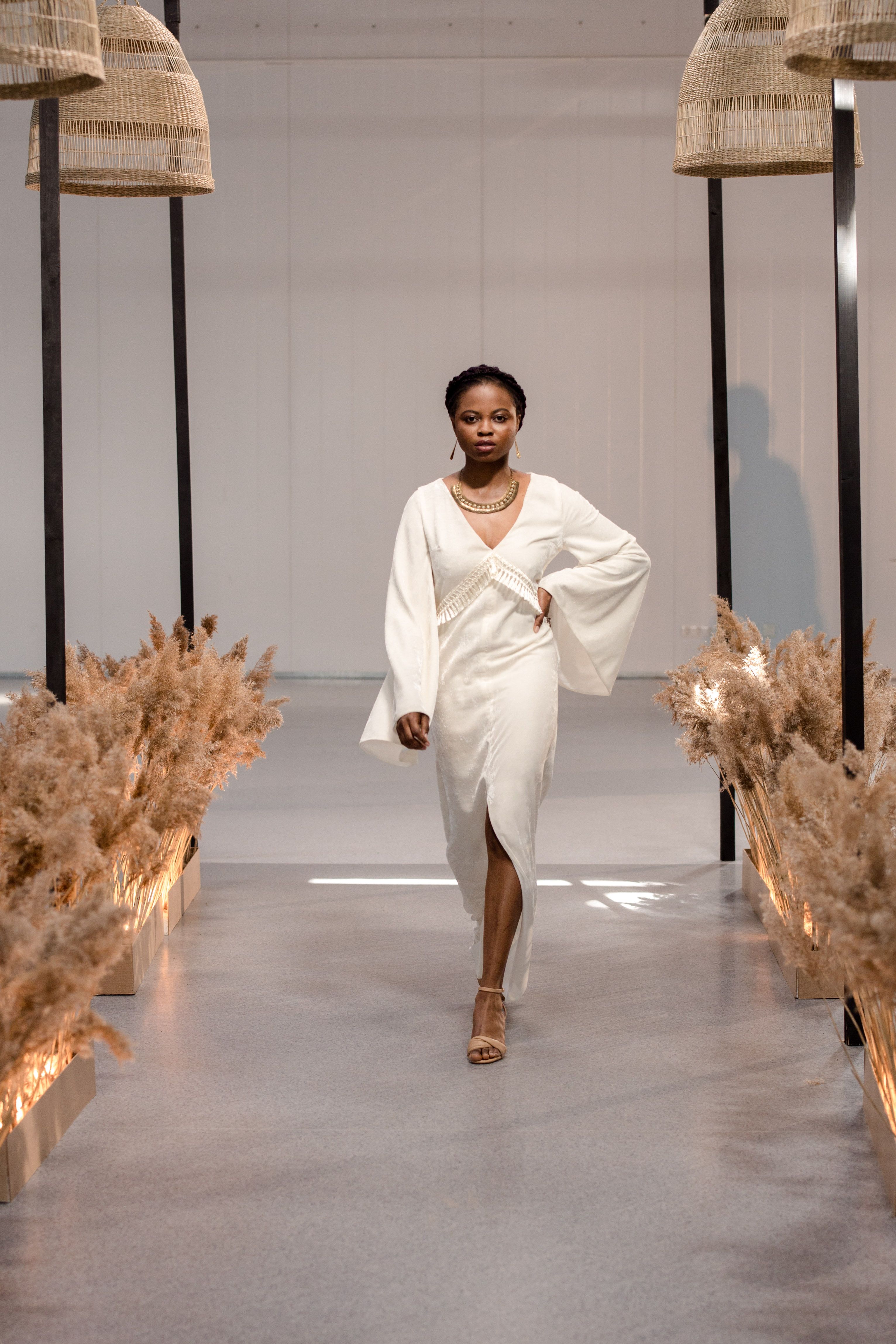 Modelo graciosa desfilando na passarela com um elegante vestido branco, exibindo tendências da moda moderna.