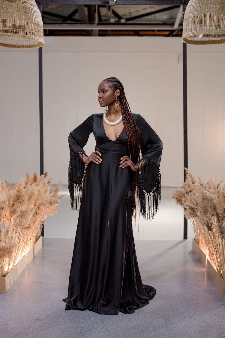 A Woman In Black Dress Posing While On The Runway