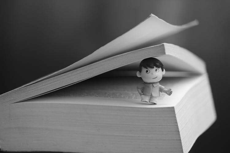 A Tiny Figure Of A Boy On A Book 