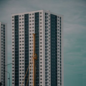 High-rise buildings in Malé with construction crane against a cloudy skyline. Modern urban architecture.
