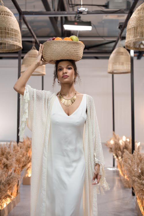 A Woman in Fashion Show Carrying Woven Basket with Fruits