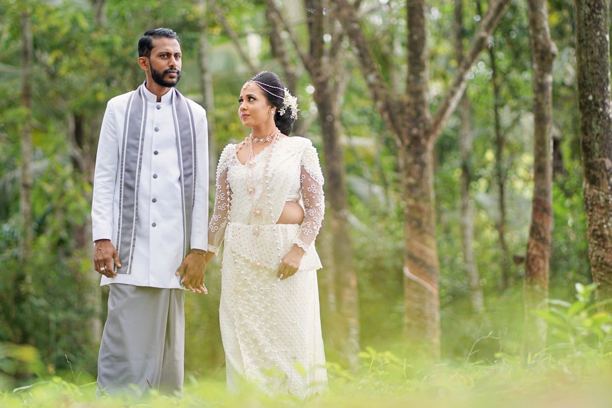 Couple in traditional Sri Lankan wedding attire in a serene forest setting