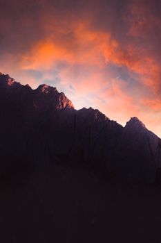 A breathtaking view of mountains silhouetted against a fiery sunset sky.