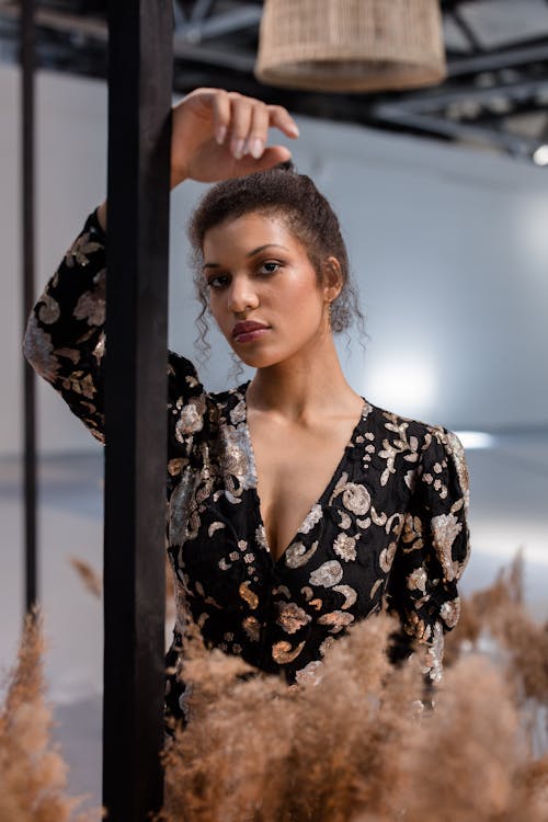 Photo of a Woman Posing with Her Hand on a Black Post