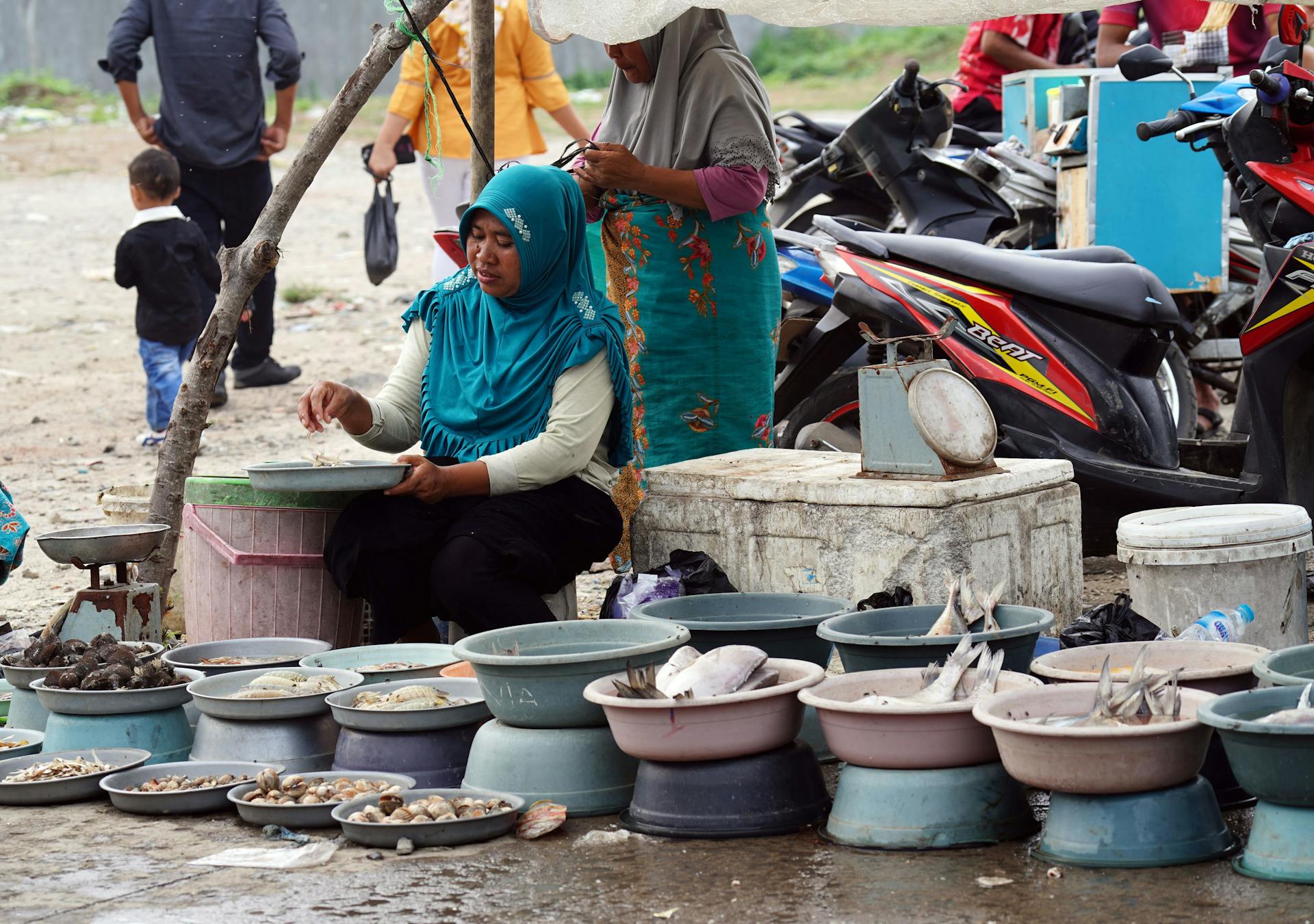 A vibrant street market scene with local merchants selling fresh seafood in basins.