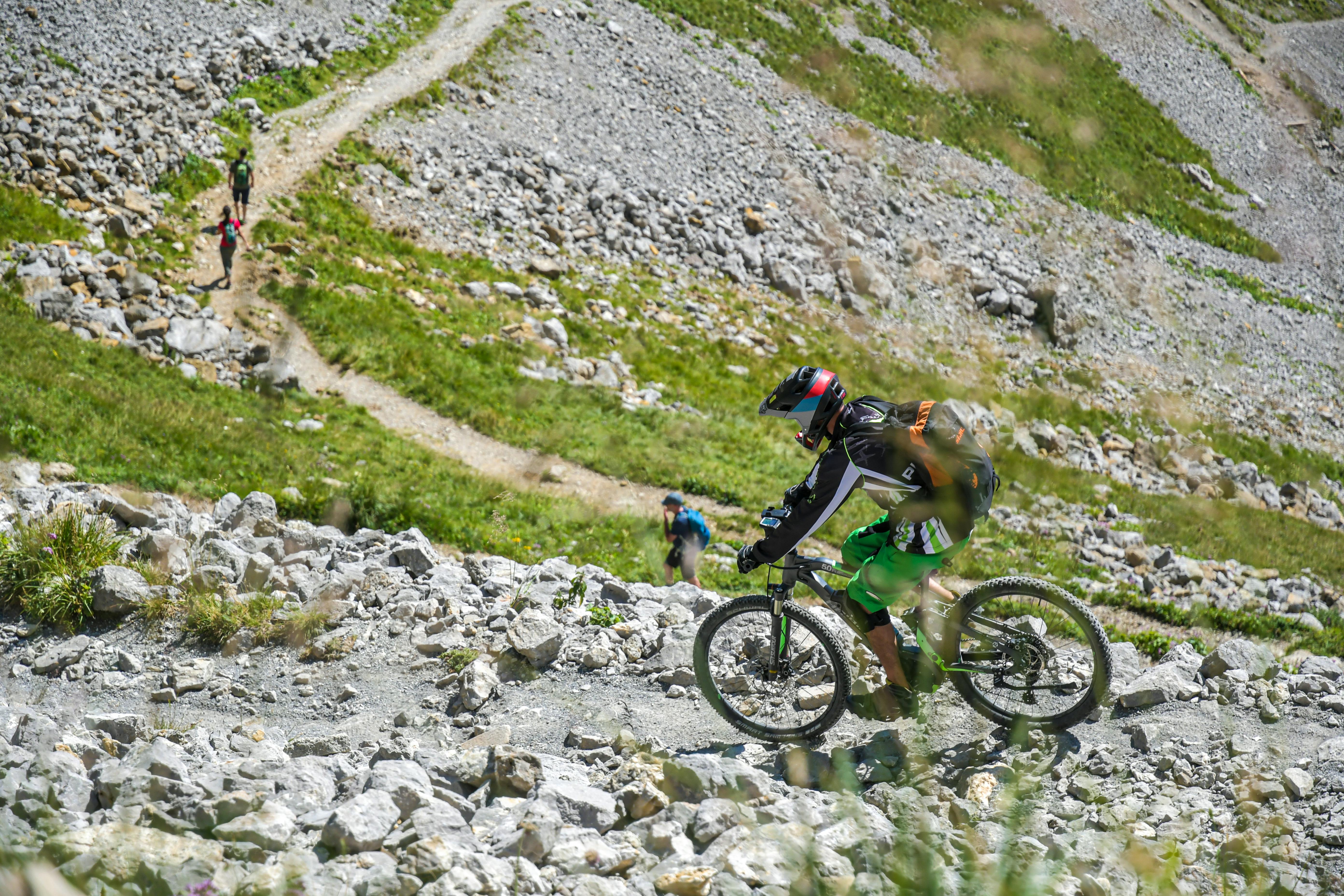 A mountain biker descends a rocky trail in Hergiswil, Switzerland, showcasing adventure and nature.
