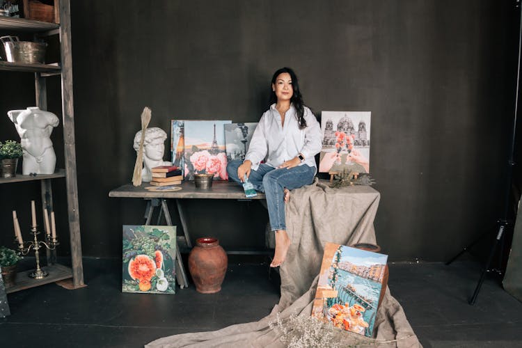 Woman Sitting In Workshop Near Paintings