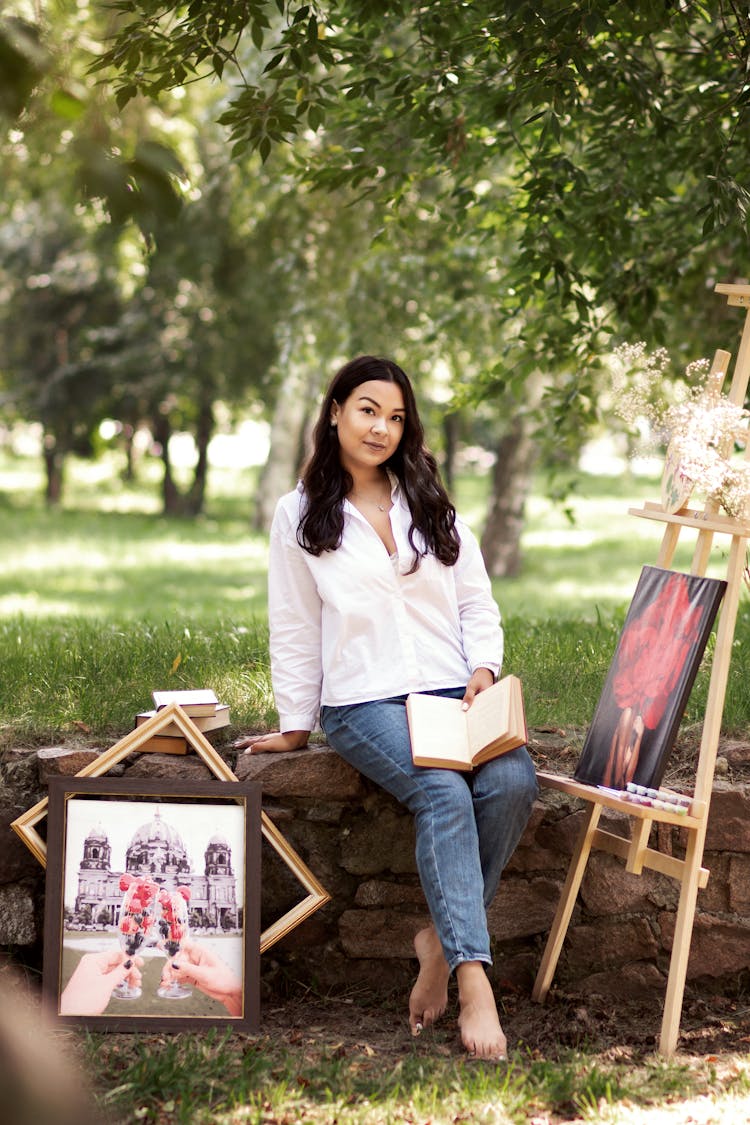 An Artist Sitting In A Park With Paintings