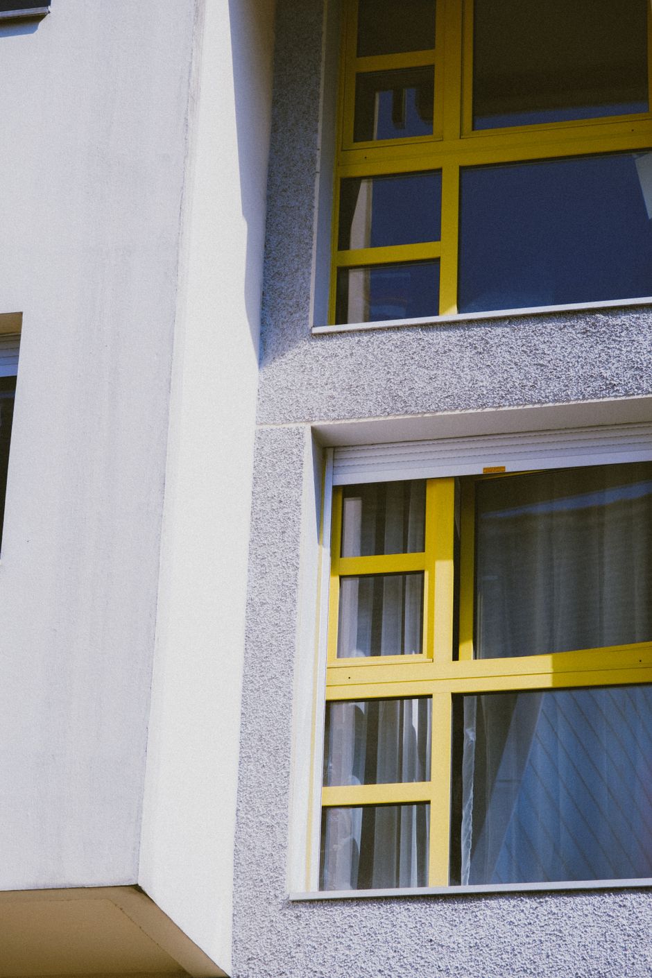 Yellow-framed windows set into a white rendered facade