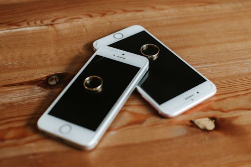 無料 茶色の木製の表面に2つのローズゴールドのi Phone6s 写真素材
