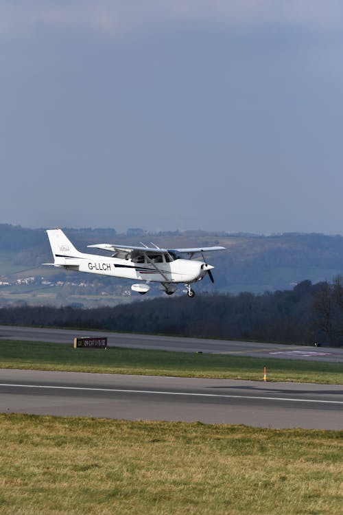 White Airplane Flying Above a Runway