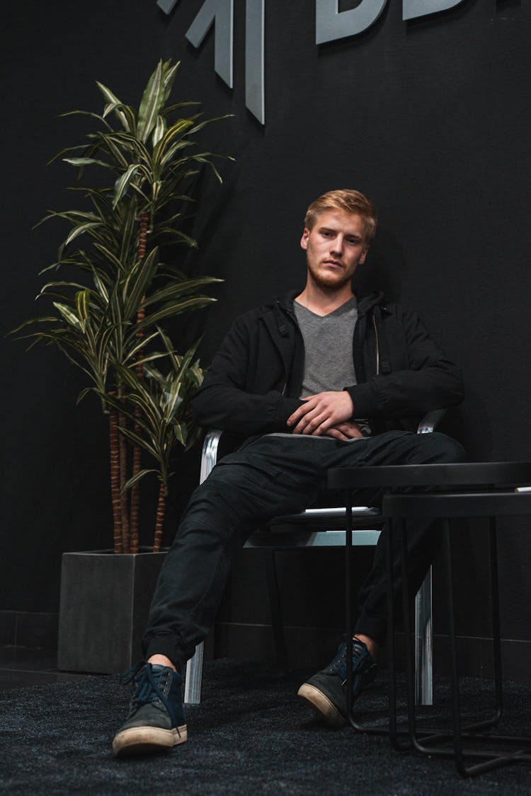 A Man In Black Clothing Sitting On A Chair