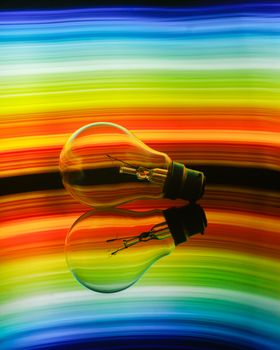 Colorful abstract of a light bulb reflecting on a surface with a vibrant rainbow gradient.