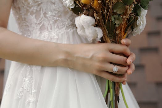 Close-up of a bride's hands holding a bouquet and displaying an engagement ring.