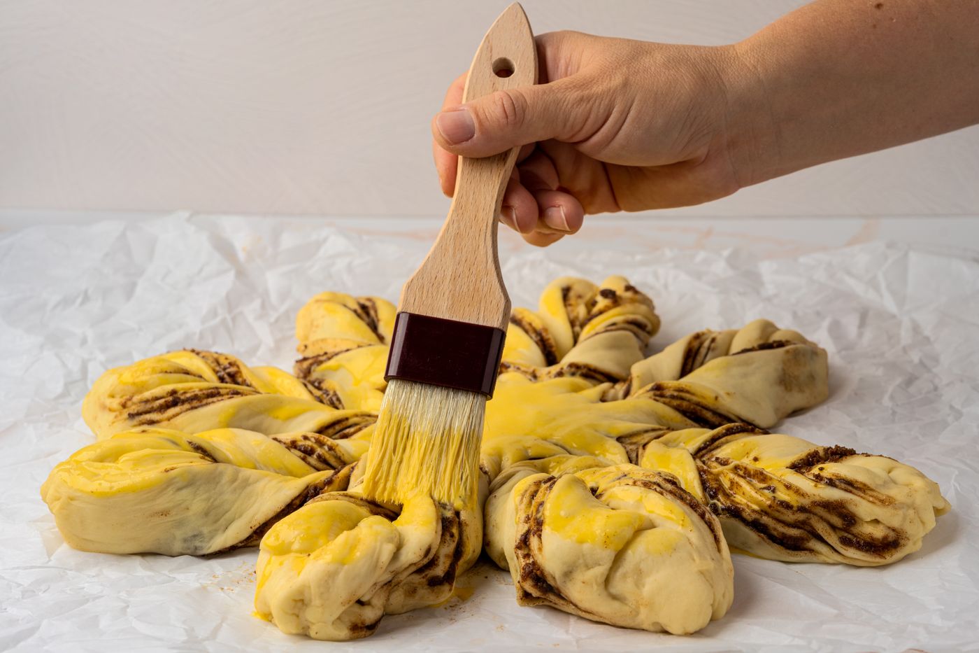 Pastry being brushed with egg wash before cooking