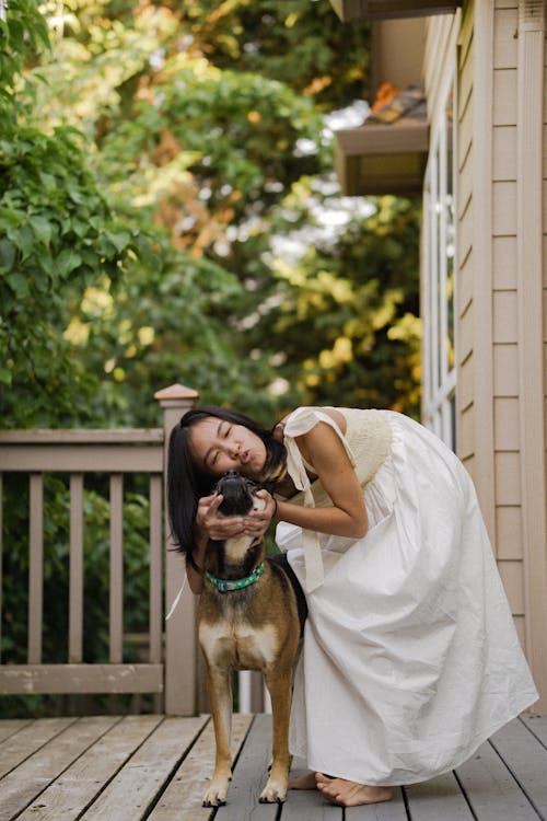 Free A Woman in White Dress Hugging Brown Dog Stock Photo