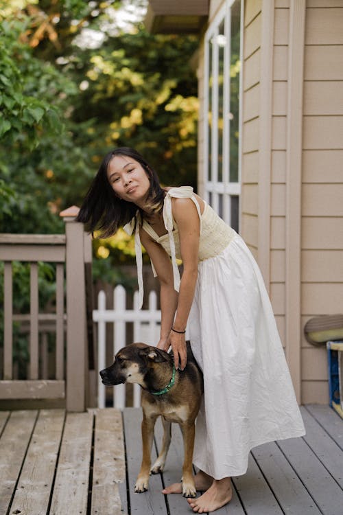 Free A Woman in a Dress Standing Beside Her Pet Dog Stock Photo