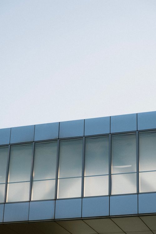 Free Elevated view of a modern building with a sleek glass facade under a clear blue sky. Stock Photo