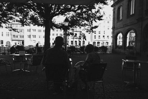 Grayscale Photo of People Sitting on Chairs