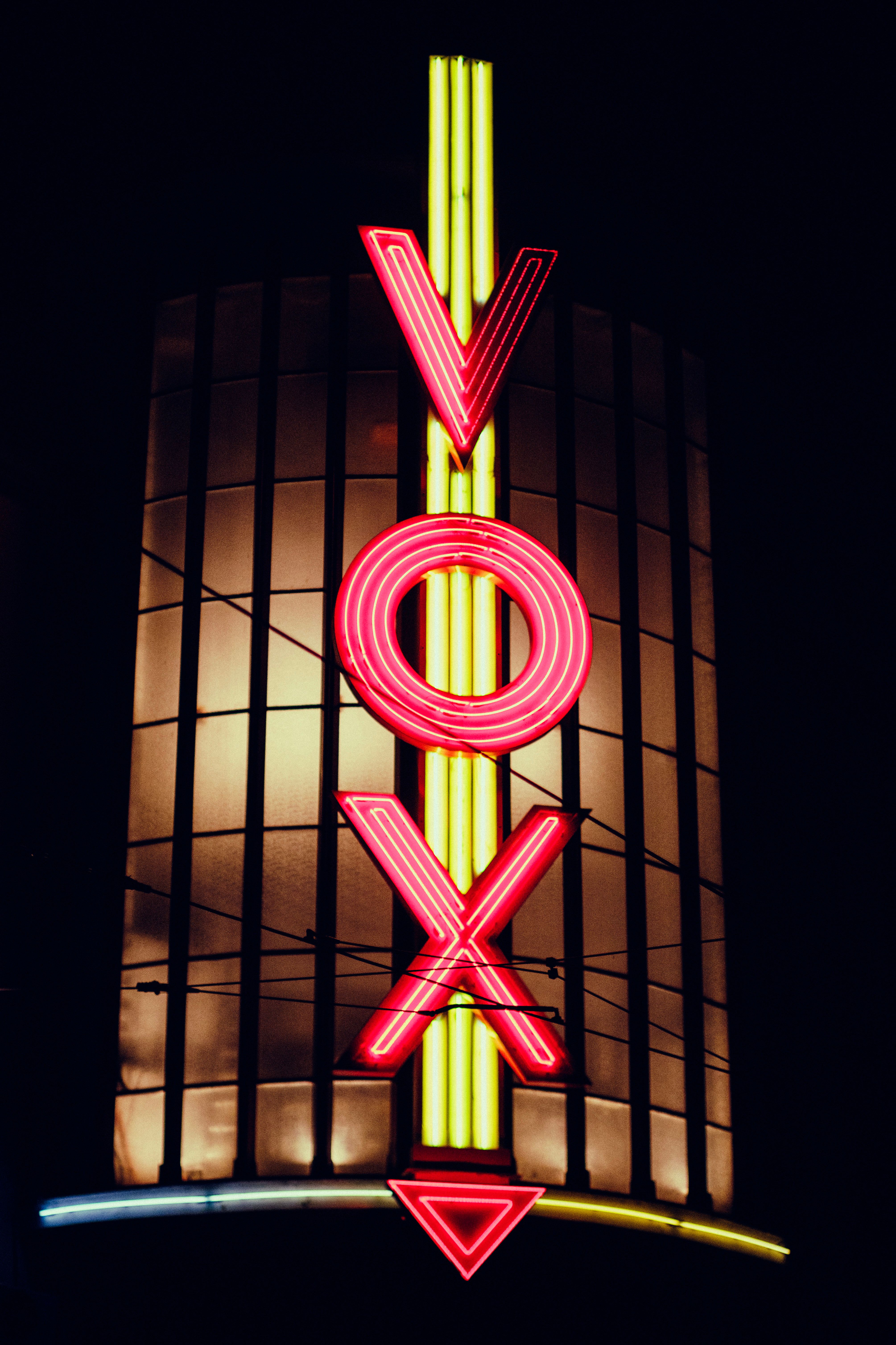 Colorful neon VOX sign glowing against glass windows in the night.