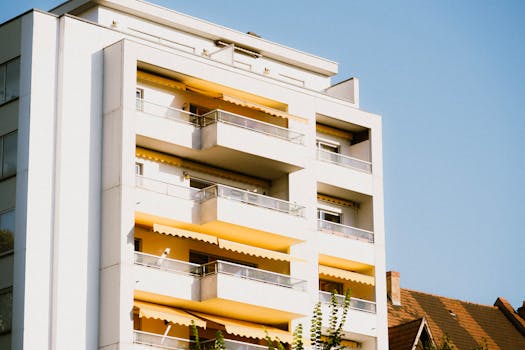 Low-angle view of a contemporary apartment building with yellow balconies against a clear sky.