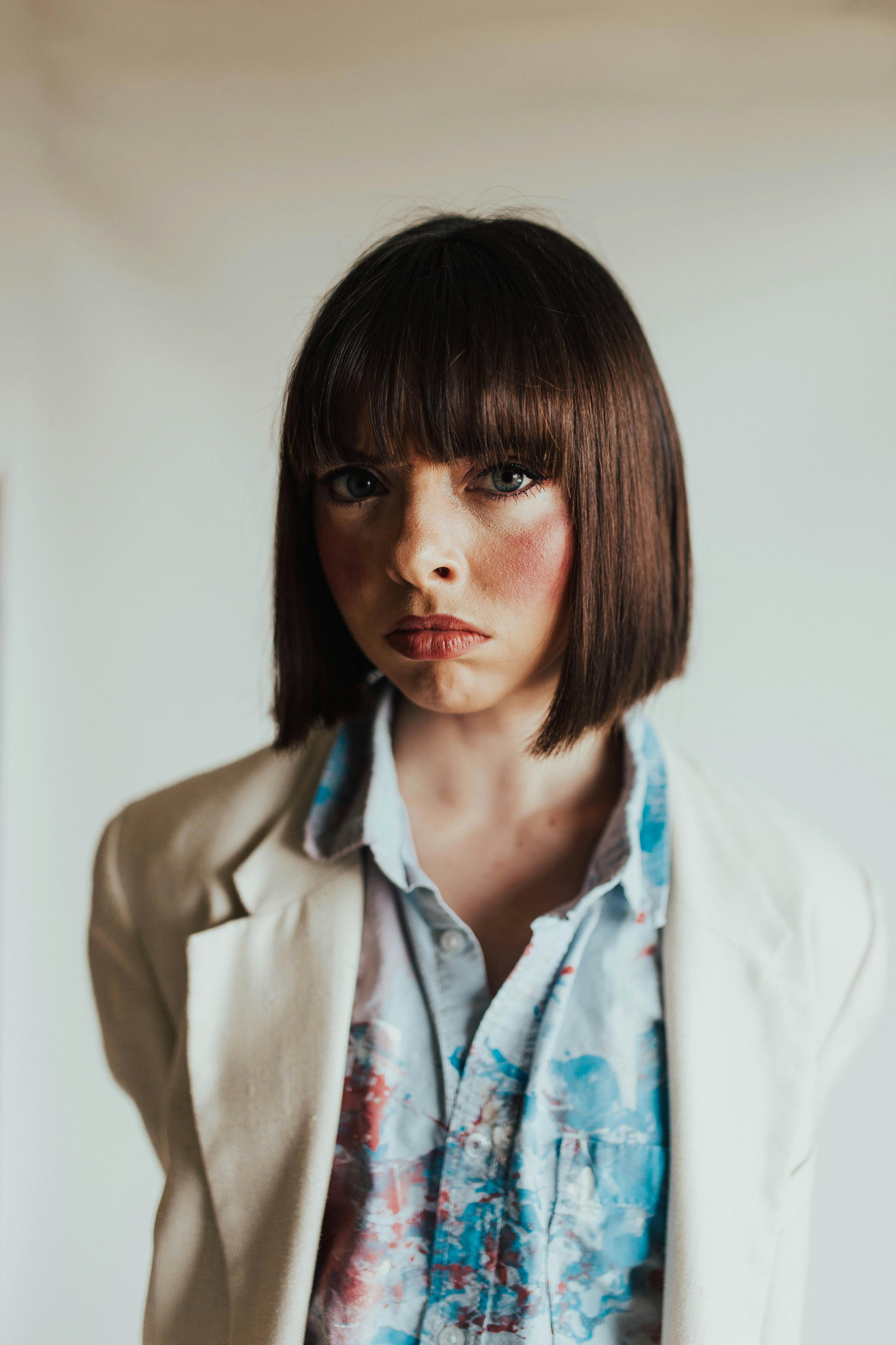 Stylish portrait of a woman with short brown hair wearing a floral shirt and blazer.